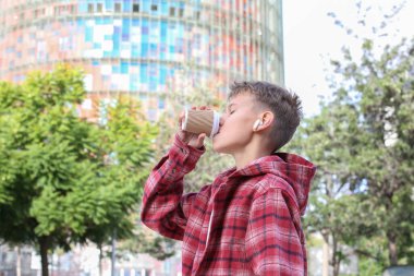 Yakışıklı genç, şehir sokaklarında dinlenmek için kahve içiyor. Kafkasyalı genç dışarıda yürüyor. 