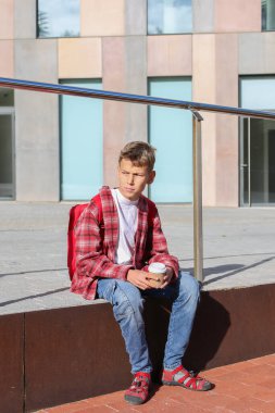 Yakışıklı genç, şehir sokaklarında dinlenmek için kahve içiyor. Kafkasyalı genç dışarıda yürüyor. 