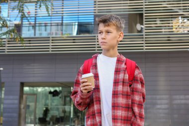 Yakışıklı genç, şehir sokaklarında dinlenmek için kahve içiyor. Kafkasyalı genç dışarıda yürüyor. 