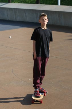 Dışarıda kaykayla duran yakışıklı bir genç. Gençler sokaklarda dolaşıp şehri keşfediyorlar.