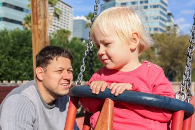 Baba, çocuk ve ergen çocuklarla dışarıda yürüyor. Çocuk parkında ailecek vakit geçireceğiz. 