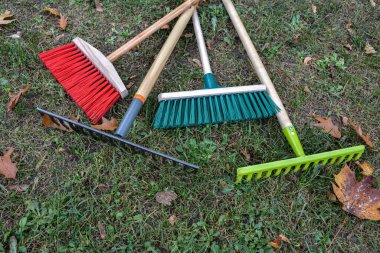 Şehir caddesini temizlemek için ekipman. Parkın çitlerinin yanında tırmık, kürek, süpürge tezgahı. Çimleri enkazdan temizlemek için hafif tırmık ve sert plastik süpürge yardımcıları..