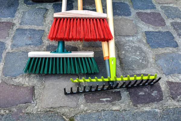 城市街道的清洁设备 扫帚站在公园栅栏旁边 轻便耙和硬塑料扫帚帮助清理草坪上的瓦砾 — 图库照片