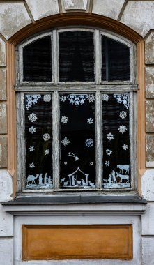 Pencerelerde el yapımı süslemelerle süslenmiş bir Noel süsü. Windows 'ta Noel süsü. Pencerelerdeki Noel süslemesi kağıttan yapılmıştır.