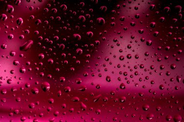 Su yüzeyinde yağ damlaları ve dalgaları olan soyut renkli arkaplan. Yansımalı sıvı damlacıkların makro çekimi. Su damlası desenli renk arkaplanı.