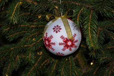 Lviv.Ukrayna. Aralık 2022. Yuvarlak el yapımı resimli Noel oyuncakları. Geleneksel halk desenli işlemeli Noel balosu. Bir Noel ağacı dalına süsleme..