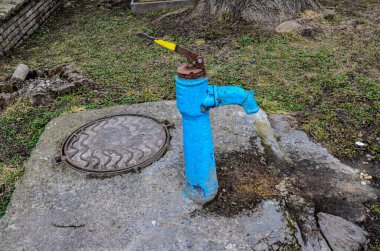 Sonbaharda eski paslı su sütunu, seçici odak, bulanık arkaplan. Köy sokaklarının arka planına karşı SSCB döneminin eski usul su musluğu..