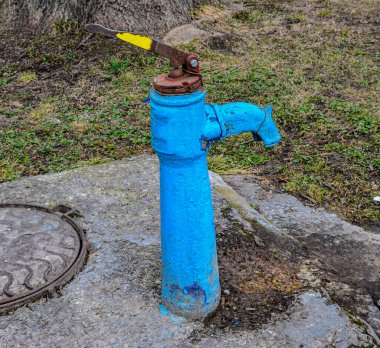 Sonbaharda eski paslı su sütunu, seçici odak, bulanık arkaplan. Köy sokaklarının arka planına karşı SSCB döneminin eski usul su musluğu..