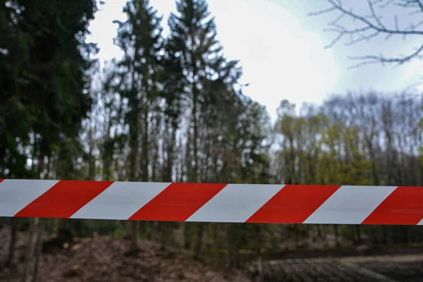 A white and red ribbon prohibits entry to the Playground.Red and white warning lines of barrier tape prohibit passage. Barrier that prohibits traffic.