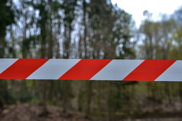 A white and red ribbon prohibits entry to the Playground.Red and white warning lines of barrier tape prohibit passage. Barrier that prohibits traffic.