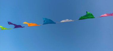 Mavi gökyüzünün önündeki renkli bayrakların çizgileri. Küçük renkli bayraklar. Mavi gökyüzüne karşı renkli üçgen bayraklar. .