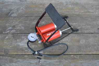 Lviv.Ukraine.November 2022.Foot pump .Red car tyre foot pump .bicycle pedal food pump on the wooden table overhead view .