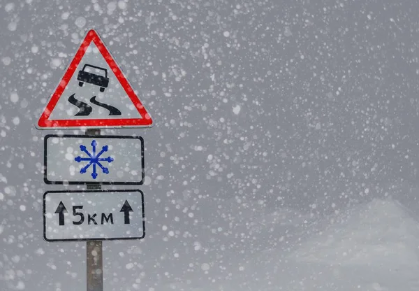 Winter road with Road sign of slippery road, direction of travel.warning sign about the snowfall on the snowy road .