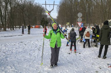 Lviv.Ukraine.January 2023.Active aged female with skiing equipment going to have ski training in winter forest .