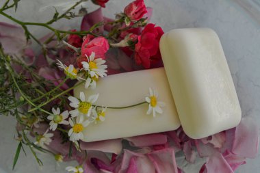 Handmade soap with rose petals, medicinal chamomile and aromatic oil.Wellness Products and Cosmetics. Spa still life with blossoms of rose and essential oils.