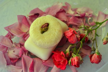 Handmade soap with rose petals, medicinal chamomile and aromatic oil.Wellness Products and Cosmetics. Spa still life with blossoms of rose and essential oils.