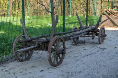 Yeşil çitin yanında eski bir ahşap araba. Rural 'da eski bir ahşap araba. Çiftlikte büyük tekerlekleri olan eski bir ahşap araba..