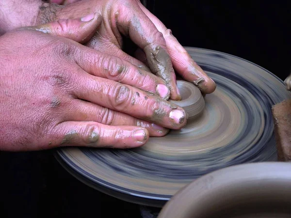 Master works on potter\'s wheel, doing blank. Hands of person sculpt pot from white clay. Workshop for manufacturing potter\'s products. Concept: handmade, workshop, artist