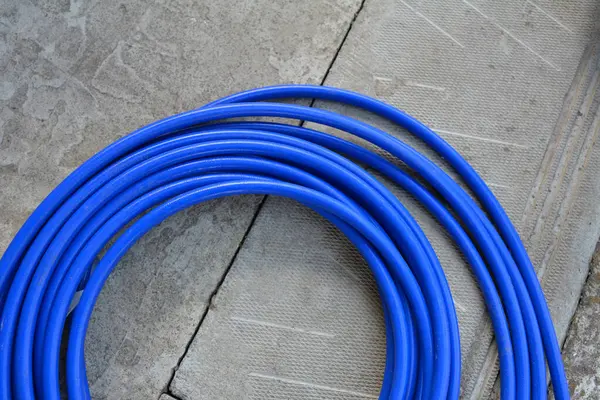 The blue hose of the spray gun is lying on the concrete.A long blue hose is wrapped in a ring.Special equipment for painting and whitewashing.