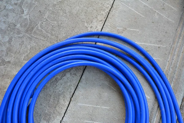 The blue hose of the spray gun is lying on the concrete.A long blue hose is wrapped in a ring.Special equipment for painting and whitewashing.