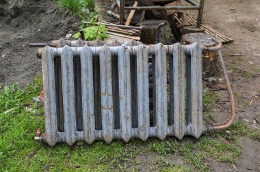 Paslı eski bir Sovyet radyatör bataryası. Demir radyatörler, kümelenmiş eski ısıtma elementleri. Yerde yatan dökme demirden yapılmış eski bataryalar..
