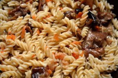 Kabaklı vejetaryen sebzeli Fusilli makarna, ahşap masada mantar ve kapari. En iyi manzara. Sıcak ve dumanı tüten tavada pişirilmiş kremalı makarna.