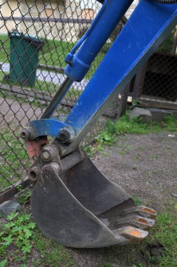 Mini kazıcı kovasını kapatıyoruz. Bahçe alanında toprağı kazıyoruz. Mini kazıcı. Mini kazıcı park etmiş, kazı işi dışarıda..