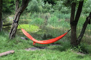 Doğal kumaştan yapılmış hamak, ağaçlardaki iplerden asılmış. Ormanda asılı hamak..