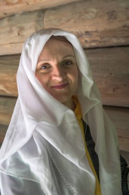 Kafasına beyaz bir pelerin takmış genç ve çekici bir kadının portresi. Dini inançlar kıyafetlerle ifade edilir..