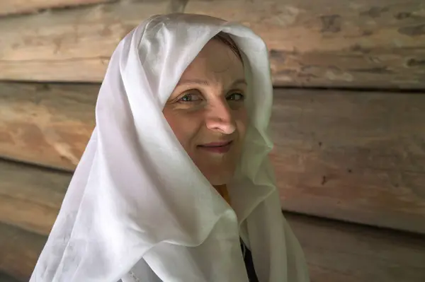 A portrait of a young, charming woman wearing a white cape on her head.religious beliefs are expressed in clothing.