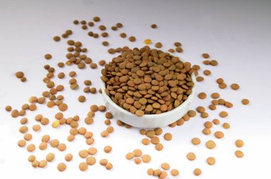 Dekoratif bir tabakta küçük yeşil mercimek taneleri. Bir kasede çiğ organik mercimek