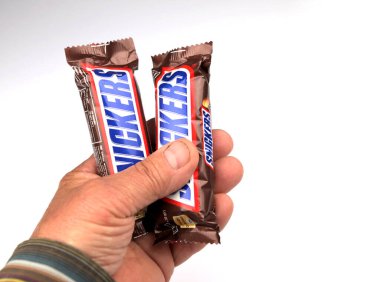 Lviv, Ukrayna. 6 Şubat 2024. Elinde iki Snickers çikolatası. Elinde Snickers çikolatası var. Snickers çikolataları Mars Anonim Şirketi tarafından üretilir..