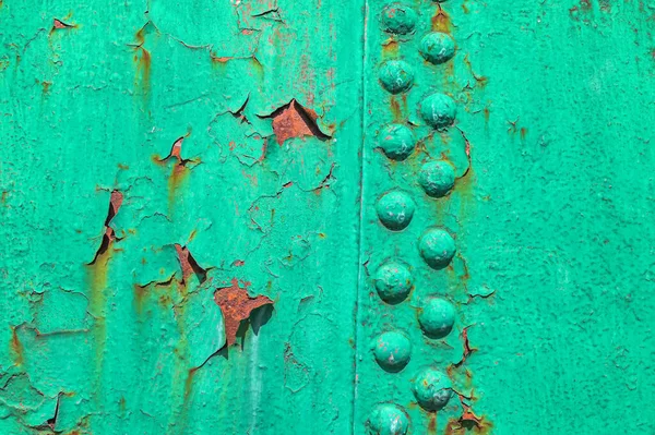 A close-up of an old aircraft side painted green.Militaristic background. Old metal surface of an airplane fuselage .
