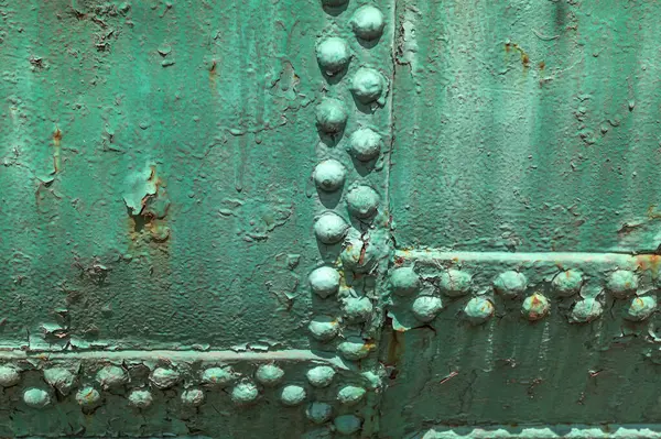 A close-up of an old aircraft side painted green.Militaristic background. Old metal surface of an airplane fuselage .