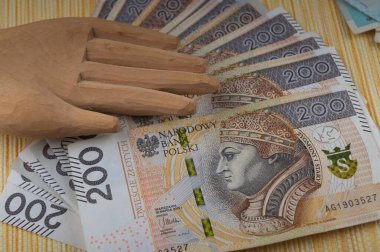 There are many copies of Polish paper money with the wooden hand of an idol on them.Excessive love of money.The concept of the financial crisis. clipart
