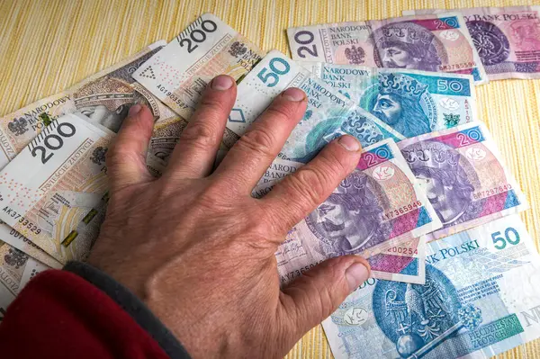 There are many copies of Polish paper money with the wooden hand of an idol on them.Excessive love of money.The concept of the financial crisis.