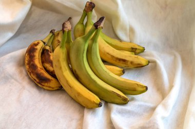 Güneş ışığında bir demet taze muz. Tahta bir masanın üzerinde sarı muz demeti. Dilimlenmiş muzla birlikte lezzetli görünüyor..