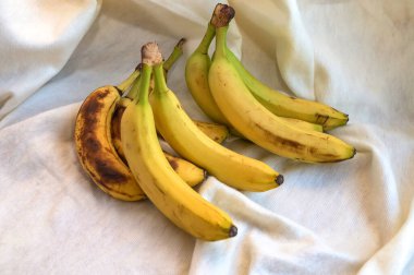 Güneş ışığında bir demet taze muz. Tahta bir masanın üzerinde sarı muz demeti. Dilimlenmiş muzla birlikte lezzetli görünüyor..