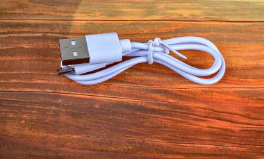 Beyaz bir USB kablosunun yakın plan görüntüsü. Beyaz bir USB tip C şarj kablosu, birçok aygıt için uyumlu, sarmal bir şekle bürünmüş, izole edilmiş..