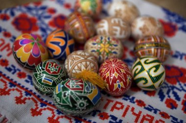Lviv. Ukrayna. 5 Mart 2025. Ukrayna 'dan Pysanka Yumurtaları. Bahar çiçeklerinin yanına yerleştirilmiş canlı renkler ve geleneksel desenler içeren çeşitli el boyalı Ukrayna Pysanka yumurtaları..