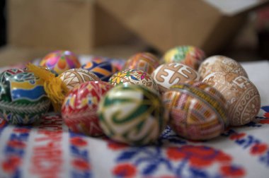 Lviv. Ukrayna. 5 Mart 2025. Ukrayna 'dan Pysanka Yumurtaları. Bahar çiçeklerinin yanına yerleştirilmiş canlı renkler ve geleneksel desenler içeren çeşitli el boyalı Ukrayna Pysanka yumurtaları..