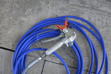 Lviv.Ukrayna. 4, 2025. Endüstriyel boya spreyi. Çeşitli yüzeyleri elle boyamak için mavi hortumla sprey boya..