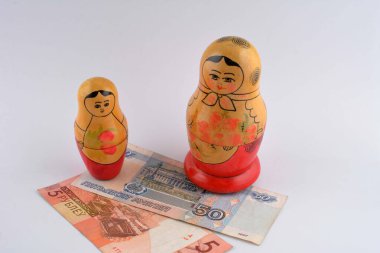 Rus Rublesi (RU) para birimi banknotu ve Rus oyuncak bebekleri ile turizm konsepti ticari ekonomik konu olarak ele alınır