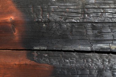 Görüntü, bir sürü siyah ve kahverengi işaretli yanmış bir ahşap yüzey. Yüzey kömürleşmiş ve kabataslak bir doku arkaplanı var. Sahne yıkım ve çürümenin bir parçasıdır. emlak sigortası
