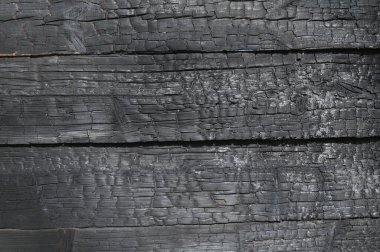 Görüntü, bir sürü siyah ve kahverengi işaretli yanmış bir ahşap yüzey. Yüzey kömürleşmiş ve kabataslak bir doku arkaplanı var. Sahne yıkım ve çürümenin bir parçasıdır. emlak sigortası