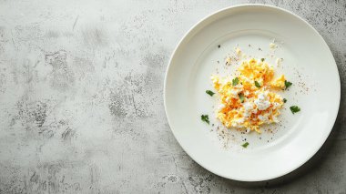 Bu görüntüde taze otlarla süslenmiş kremalı yumurtalar ve şık bir tabakta kırmızı biber var. Kahvaltı ya da kahvaltı için mükemmel..