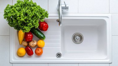 Temiz bir mutfak lavabosuna yerleştirilmiş taze sebze ve meyvelerin renkli çeşitleri. Lezzetli yemekler pişirmek için ideal sağlıklı malzemeler sergiliyorlar..