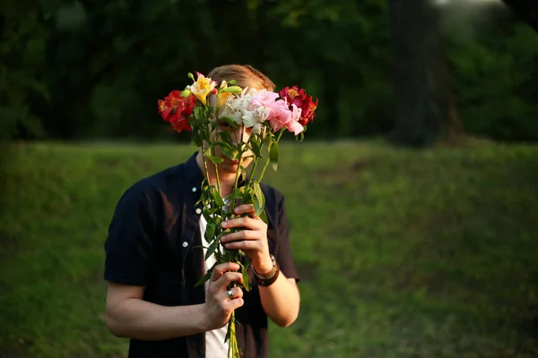 man in a black shirt with a bouquet of flowers above his head
