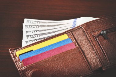 Yüz dolarlık banknotlar ve banka kartlarıyla dolu açık deri bir cüzdanın yakın çekimi. Yüksek bir açıdan..