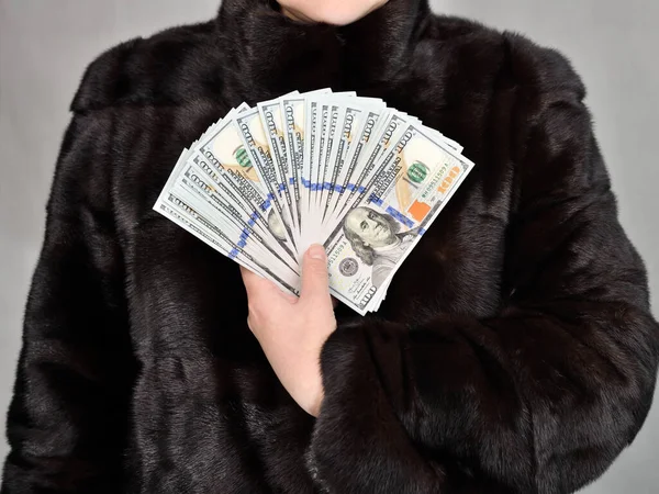ミンクコートの女性は彼女の手に多くの百ドル札を持っている 正面図 スタジオショット — ストック写真